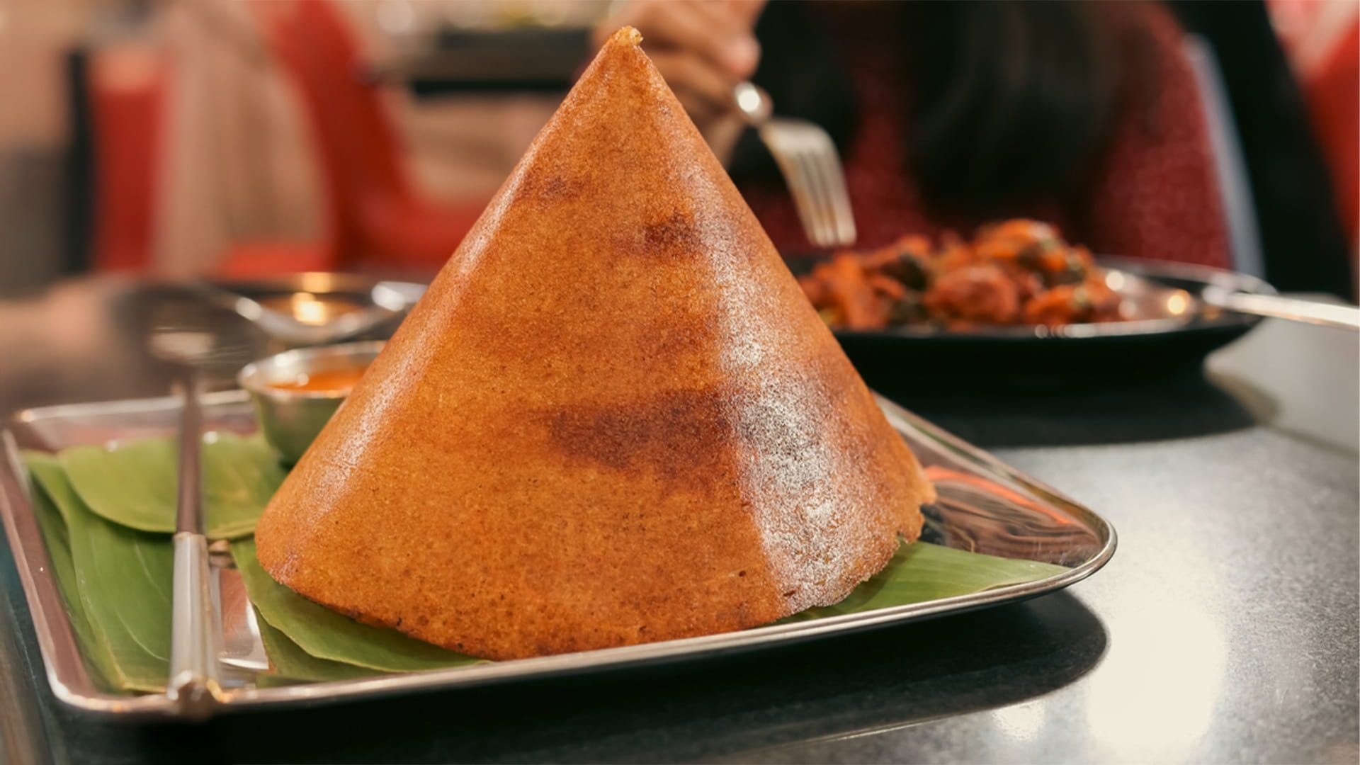 Crispy South Indian cone dosa served on a banana leaf with traditional chutneys at an Indian restaurant in Canberra